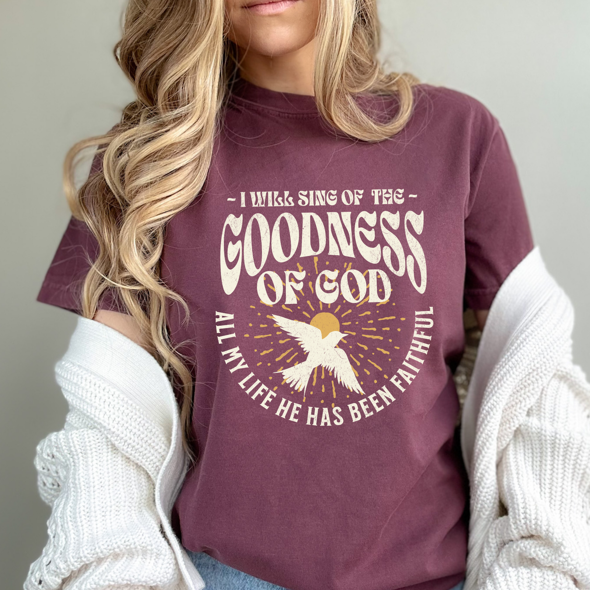 Unisex Christian T-shirt with a vintage style design that says "I will sing of the goodness of God. All my life he has been faithful". The design is direct to garment (DTG) printed on a vineyard-colored Comfort Colors brand t-shirt and available in sizes S-3XL.